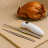 Weißes elektrisches Tranchiermesser mit zwei Edelstahlklingen auf einem braunen Schneidebrett, mit einem gebratenen Hähnchen im Hintergrund Anteprima dell’immagine prodotto
