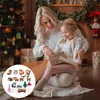 A mother and daughter are opening a Christmas gift in a festive setting with a Christmas tree and decorations. Produktbild-Vorschau