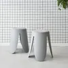 Two gray stools with textured bouclé seats are placed in front of a white wall with a black grid pattern. Produktbild-Vorschau