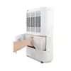 A person's hand is shown removing a water tank from a white dehumidifier. Podgląd zdjęcia produktu