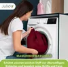 A woman is putting a burgundy fabric into a washing machine. Produktbild-Vorschau