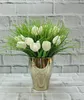 A bouquet of white tulips and green grass in a gold ceramic vase against a brick wall. Anteprima dell’immagine prodotto