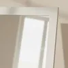 A close-up view of the corner of a white mirror frame, with light casting shadows on the wall behind it. Náhľad obrázku produktu