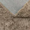 A close-up view of the texture of a fluffy brown rug and its backing. Produktbild-Vorschau