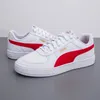 A pair of white Puma sneakers with red accents and gold branding, displayed on a gray surface against a white background. Produktbild-Vorschau