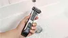 A hand holding a Philips Bodygroom Series 7000 electric shaver under running water in a sink. Podgląd zdjęcia produktu