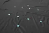 A black tarp with scattered light blue petals. Produktbild-Vorschau