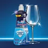 A bottle of Finish dishwasher rinse aid is shown next to a sparkling clean wine glass against a blue gradient background. Podgląd zdjęcia produktu