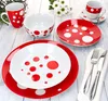 A set of red and white polka dot dinnerware arranged on a light wooden table. Produktbild-Vorschau