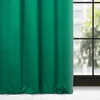 A green curtain is shown hanging in front of a window with a view of trees and buildings. Produktbild-Vorschau
