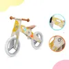 A wooden balance bike with yellow and white wave pattern, shown with close-up insets highlighting details. Náhľad obrázku produktu