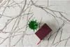 A rug with a branch pattern, a small potted plant, and a book. Náhled obrázku produktu