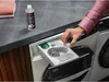 A person is pouring liquid from a small bottle into a washing machine detergent drawer. Produktbild-Vorschau