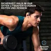 A man is working out in a gym, lifting weights and wearing earbuds. Produktbild-Vorschau