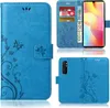 A collage of images showing a blue flip phone case with a floral and butterfly design. Produktbild-Vorschau