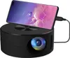A black portable projector with a smartphone placed on top, connected by a cable. Produktbild-Vorschau