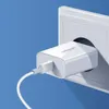 A white USB charger plugged into a white wall socket against a blue background. Náhled obrázku produktu