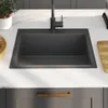 A black kitchen sink with a black faucet is installed on a white countertop. Voir les images du produit
