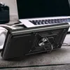 A black phone case with a ring stand is placed on a wooden surface, with a laptop and headphones in the background. Produktbild-Vorschau