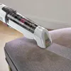 A handheld vacuum cleaner is being used to clean a fabric surface. Podgląd zdjęcia produktu