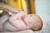 A person is changing a baby's diaper. Anteprima dell’immagine prodotto