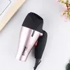 A rose gold and black hairdryer is placed on a white surface with some decorative flowers and a wooden frame in the background. Produktbild-Vorschau