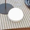 A white, spherical light is placed on a striped tablecloth next to a dark gray base of a lamp. Produktbild-Vorschau