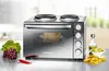 A multi-functional oven with two stovetop burners is displayed on a kitchen counter with fresh produce and food items. Produktbild-Vorschau