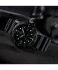 A close-up shot of a black Luminox watch with a black rubber strap, set against a dark, textured background. Produktbild-Vorschau