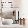 A folded portable bed is shown next to a sofa in a living room setting, with text overlay highlighting its features. Voir les images du produit