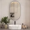 A modern bathroom vanity with a marble-effect sink, a black faucet, and an oval illuminated mirror above. Accessories like soap dispensers, toothbrushes, and candles are arranged on the counter. Produktbild-Vorschau