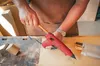 A person is using a red hot glue gun to repair wood in a workshop. Anteprima dell’immagine prodotto