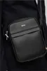 A person wearing a black jacket and a black BOSS messenger bag. Anteprima dell’immagine prodotto