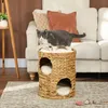 A cat is standing on a woven cat tower in a living room setting. Produktbild-Vorschau