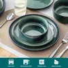 A table setting with green stoneware dishes, cutlery, and a glass of water. Náhled obrázku produktu