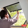 A man is adjusting a screen on a skylight window, with trees visible outside. Voir les images du produit