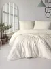 A neatly made bed with beige bedding in a bright room. Produktbild-Vorschau