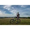 A man on a mountain bike in a grassy field with a cloudy sky. Náhled obrázku produktu