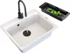 A white kitchen sink with a black faucet and a black colander filled with cucumbers. Podgląd zdjęcia produktu