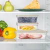A refrigerator shelf with various food items stored in clear plastic containers. Produktbild-Vorschau