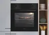 A built-in oven with a pizza inside, placed in a kitchen setting with shelves and bowls on the side. Náhľad obrázku produktu