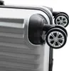 A close-up view of the wheels and corner of a silver suitcase. Produktbild-Vorschau