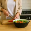 A person is chopping tomatoes to add to a salad in a large bowl. Podgląd zdjęcia produktu