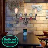 A vintage-style pipe lamp with three bulbs is mounted on a brick wall above a table. Náhled obrázku produktu