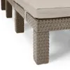 A close-up view of the leg and base of a wicker-style chaise lounge with a beige cushion. Voir les images du produit