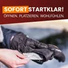 A person's hands are shown inserting a hand warmer into a black glove in a snowy outdoor environment. Náhled obrázku produktu