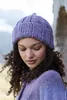 A woman wearing a knitted hat and sweater outdoors. Produktbild-Vorschau