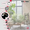 A plant stand is shown in a living room setting with plants and furniture. Produktbild-Vorschau