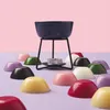 A collection of colorful wax melts arranged around a dark blue wax melt warmer with a lit tea light candle underneath. Anteprima dell’immagine prodotto