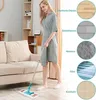 A woman is cleaning a floor with a mop in a living room setting. Produktbild-Vorschau